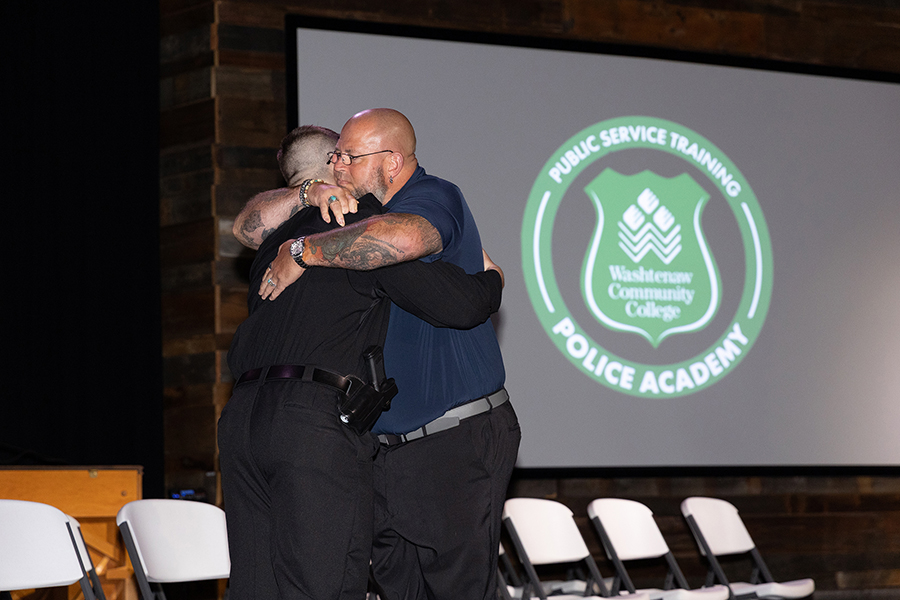 Police Academy graduate being hugged by his father